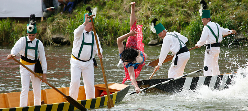A men, dresses as a woman, falls into the water during the Fischerstechen